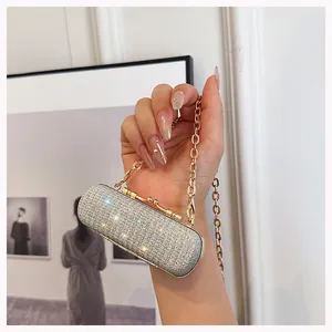 Close-up of mini silver rhinestone clutch bag with gold metal frame and chain strap