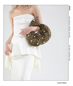 Detail of leopard print tote bag with silver studs worn by a model in white dress