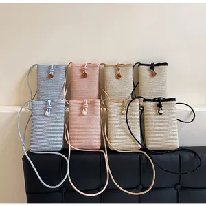 Detail of hand-woven straw mini crossbody bags with wooden buttons in four pastel colors