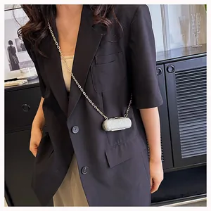 Detailed view of mini silver rhinestone cylinder crossbody bag with golden chain strap