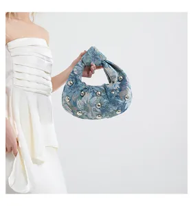 Detail view of the floral jacquard fabric with silver rivets on this hobo shoulder bag