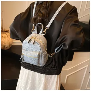 Detailed back view of a light blue floral mini backpack with gold hardware on a model