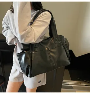 Detail of a large black tote bag with multiple exterior pockets and a wide shoulder strap