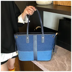 Détail du grand sac cabas en denim contrasté avec lanières en cuir et anneaux dorés