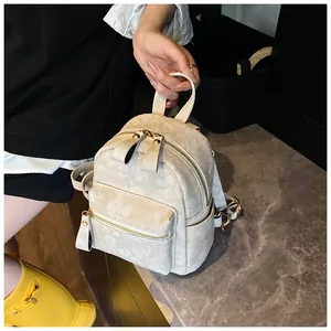Detailed shot of a cream mini backpack featuring subtle floral patterns and gold zippers