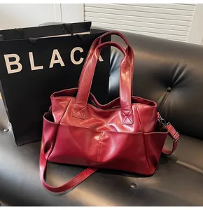Burgundy matte leather tote bag detail with side pockets and adjustable crossbody strap