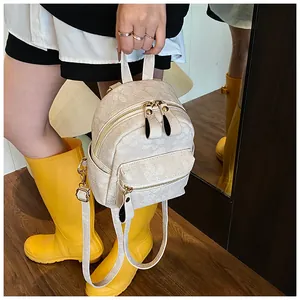 Detail of a mini cream-colored floral textured backpack with elegant gold hardware