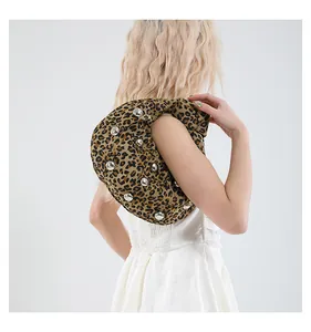 Detail of leopard print handbag with silver studs on soft fabric and crescent handle