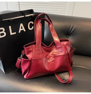 Detail view of large burgundy tote bag with double handles and adjustable shoulder strap
