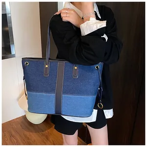 Détail du sac cabas en denim bicolore avec surpiqûres blanches et boucles dorées