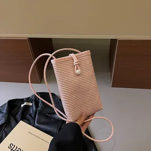 Pink straw woven mini crossbody phone bag with leather trim and decorative pearl button