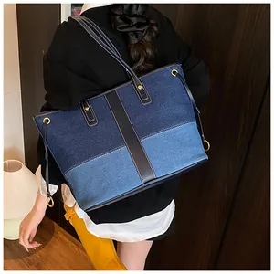 Détail du cabas en denim contrasté avec garniture en cuir et rivets dorés brillants