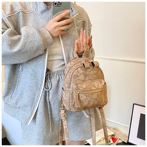 Detailed macro of a khaki mini backpack with vintage print and gold hardware zippers