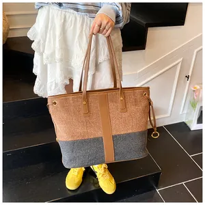Détail du sac cabas en denim contrasté montrant des textures riches et un décor d'anneau en métal