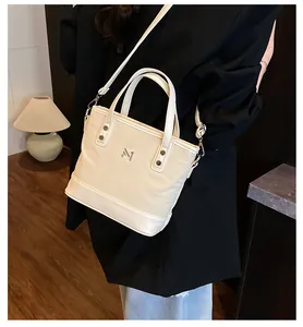 Detail of cream white tote bag with metallic M logo and adjustable shoulder strap