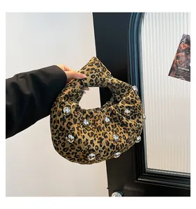 Detail of leopard print underarm bag featuring decorative silver metal studs and knotted handle