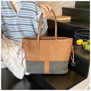 Détail d'un grand sac cabas contrasté avec garniture en cuir brun et anneaux dorés