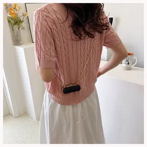 Close-up of pink cable knit short sleeve sweater with a black glitter mini chain bag