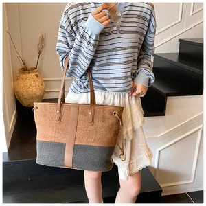 Détail du cabas vintage en denim montrant les poignées en cuir et les accents métalliques