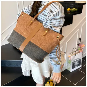 Détail du sac cabas bicolore en tissu marron et gris avec anneaux métalliques dorés