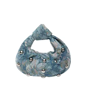 Retro blue floral jacquard tote with knot handle and silver studs on white backdrop