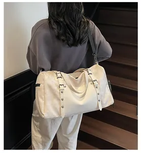 Detalle del bolso de viaje crema con logo XINGJIU sobre tela texturizada y cuero