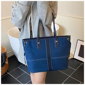 Détail du grand sac cabas en denim bleu foncé avec surpiqûres blanches et rivets dorés