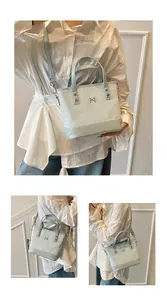 Detail view of light blue tote bag with metallic logo and adjustable shoulder strap