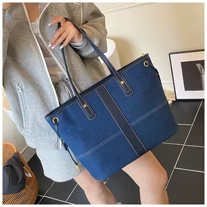 Vue détaillée du cabas en denim avec surpiqûres contrastées et œillets métalliques