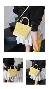 Detail view of yellow canvas tote bag with leather base and silver metal logo