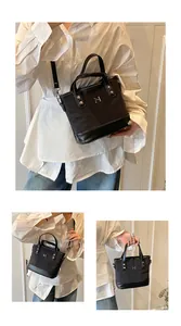 Detail view of black canvas tote bag with reinforced leather handles and silver metal M logo
