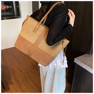 Détail d'un grand sac fourre-tout tissé beige et marron avec anses en cuir sur mannequin