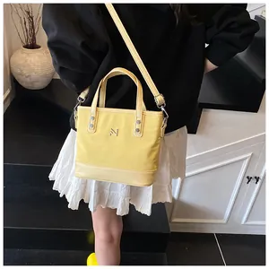 Detail of light yellow canvas tote bag with leather trim and adjustable shoulder strap
