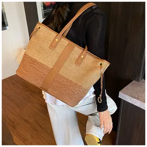 Détail du grand sac cabas tissé avec anses en cuir et rivets métalliques sur l'épaule