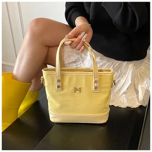 Detail of yellow canvas tote bag with leather straps and metal N1 logo decoration