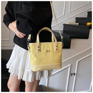 Detail of light yellow tote bag with metallic M logo and reinforced base protection