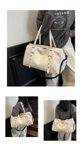Detalle de la bolsa de viaje crema con textura de cuero, remaches y hebillas decorativas