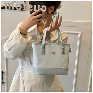 Detail of light blue tote bag with metallic N-logo and textile leather trim