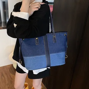 Sac cabas en jean contrasté avec design patchwork bleu porté par un mannequin en studio