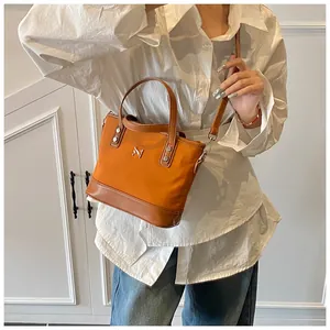Detail of orange canvas tote with brown leather handles and a metallic N logo
