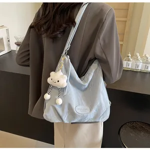 Détail du sac fourre-tout plissé bleu clair avec un charm nuage en peluche sur la bandoulière