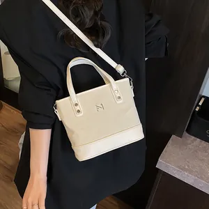 Beige tote bag with leather trim and N logo, shown with adjustable shoulder strap