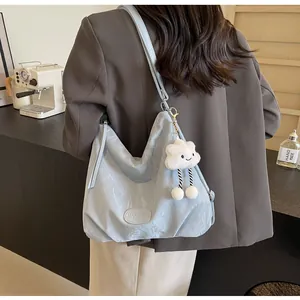 Gros plan sur un sac d'épaule en nylon bleu clair avec pendentif nuage et logo de marque
