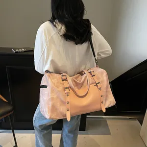 Bolso de viaje rosa de cuero sintético con remaches y correa en un entorno de estilo de vida