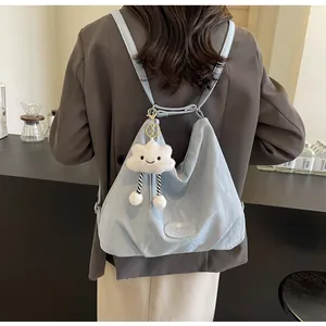 Détail d'un sac à dos bleu clair texturé avec logo et charme de nuage en peluche