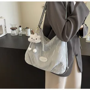 Détail du sac argenté métallisé avec bandoulière rayée et breloque nuage en peluche