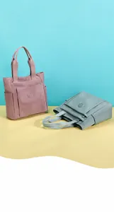Detail of high-capacity nylon tote bags in pink and grey with reinforced stitching