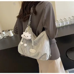 Détail du sac fourre-tout argenté plissé avec charm nuage dans un café minimaliste