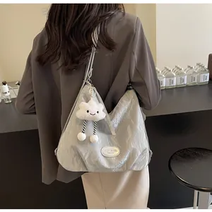 Grand sac cabas gris texturé porté à l'épaule par un mannequin avec pendentif
