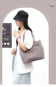 Detail of taupe nylon tote bag featuring front pocket and circular embossed emblem